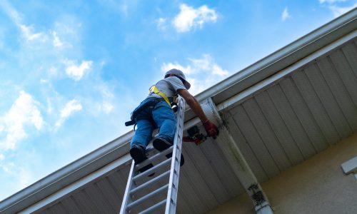 Ken's Gutters employee inspecting a downspout and gutter system.